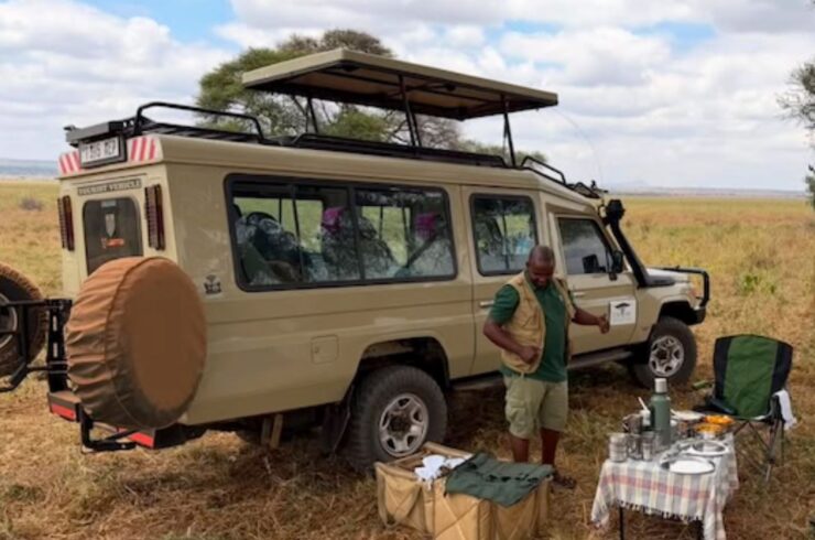 Tanzaniaanse gids met safari-jeep tijdens een safari door Noord-Tanzania
